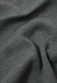 Tessuto grigio a costine con una consistenza morbida, caratterizzato da una leggera lucentezza. Il materiale presenta un motivo intrecciato, che suggerisce calore e comfort.