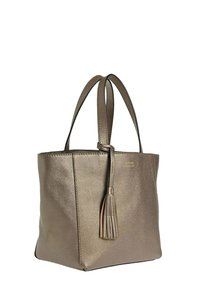 Sac fourre-tout en cuir bronze métallisé avec doubles poignées et un accent de pampille suspendue sur fond blanc.