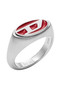 Stříbrný prsten z nerezové oceli s hladkým, broušeným páskem. Obsahuje velký oválný design s červeno-bílým vsazením na vrchu, značeno "DIESEL" uvnitř.