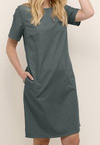 Vestido gris oscuro de manga corta con un corte holgado, escote redondeado, bolsillos laterales y una tela suave y texturizada.
