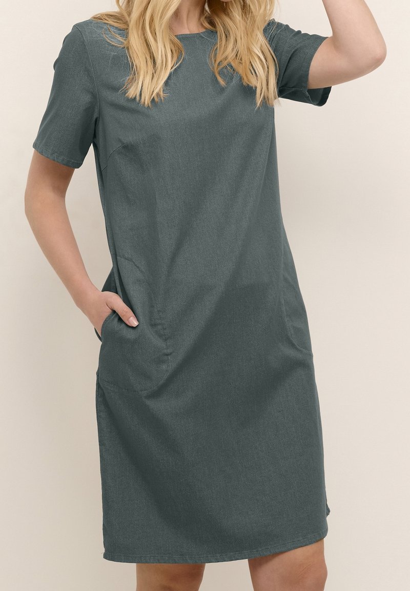 Vestido gris oscuro de manga corta con un corte holgado, escote redondeado, bolsillos laterales y una tela suave y texturizada.