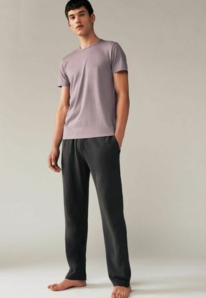Tricou din bumbac de culoare purpurie, cu mâneci scurte, asortat cu pantaloni relaxați de culoare gri închis. Ambele articole au un design neted și casual.