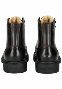 Braune Leder-Stiefeletten mit glatter Textur, runder Spitze und schwarzen Gummisohlen. Verfügt über dekorative Nähte und ein Logo an der Ferse.