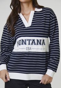Maglietta a maniche lunghe a righe blu marine e bianche con colletto, caratterizzata dalla scritta "MONTANA USA" al centro. Presenta polsini a coste e vestibilità comoda.