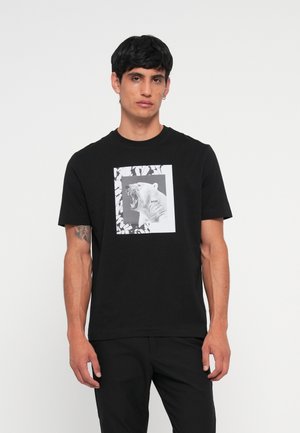 Tricou negru din bumbac cu un grafic frontal al unui urs polar răcnet în alb și negru, încadrat de o margine rectangulară cu modele de frunze.
