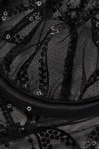 Tela de encaje negra con intrincados patrones texturizados y brillo de lentejuelas. Ribeteada con satén negro liso a lo largo de los bordes.