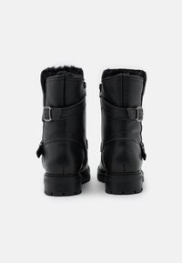Botas de cuero negro hasta el tobillo con superficie texturizada, forro de piel en la parte superior y correas ajustables con hebillas a los lados para mayor estilo y ajuste.