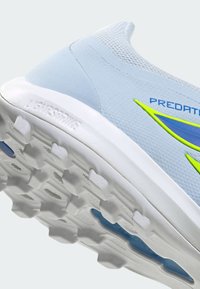 Chaussure de sport bleu clair avec semelle texturée et marquage "Predator", avec une semelle intermédiaire blanche et des accents vert néon et bleu.
