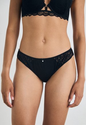Black lace panties with sheer panels and a decorative silver accent at the front. The fabric features a delicate floral pattern.