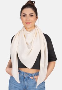 Écharpe triangulaire blanche en tissu texturé et froissé, drapée élégamment autour du cou, contrastant avec un top noir court.