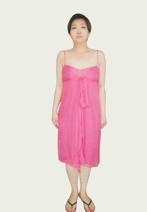 Robe rose sans manches avec un détail noué à l'avant, fabriquée dans un tissu léger. Présente une coupe ample, tombant à mi-mollet.