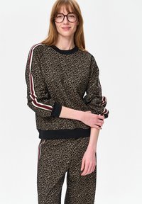 Leopardprint sweater met zwarte geribde boorden bij de mouwen en zoom, met rode en witte strepen langs de mouwen. Zachte, gestructureerde stof.