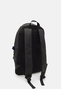 Svart ryggsäck med en slät yta och bakpanel av mesh. Utrustad med vadderade axelremmar och ett handtag på toppen, designad för komfort och stöd.