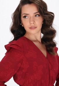 Cremfarbendes Kleid mit strukturiertem floralem Stickerei, Rüschen-Schultern und tiefem V-Ausschnitt. Glattes Material und sanfter Glanz steigern die visuelle Anziehungskraft.
