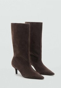 Bottines en suédine marron avec un bout pointu et un talon slim et bas. Texture lisse et silhouette élégante et près du corps.