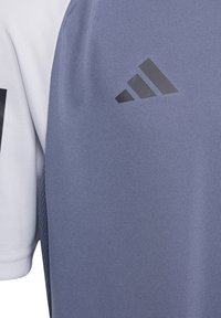 Blau-weißes Sport-Shirt aus strukturiertem Stoff, mit einem schwarzen Adidas-Logo auf der linken Brustseite und einem Raglanärmel-Design.