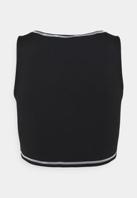 Svart sportig crop top med rund halsringning och ärmlös design. Har en kontrasterande vit söm längs kanterna. Slät textur.