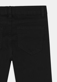 Zwarte denim jeans met een fitted ontwerp, voorzien van een enkele achterzak, verticale naden en een effen tailleband. Glad textuur.
