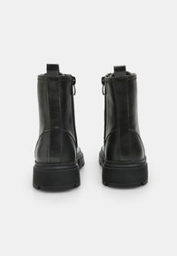 Svarta läderankelboots med en strukturerad yta, med sidodragkedjor, en robust gummisula och en dragflik bak.