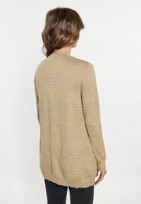 Cardigan beige con righe orizzontali più chiare, una texture morbida, maniche lunghe e un retro leggermente più lungo dotato di tasche laterali.