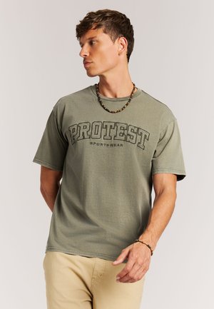Kaki groene T-shirt met korte mouwen, gemaakt van katoen, met een opvallend, verdiept "PROTEST" logo in het zwart. De T-shirt heeft een ontspannen pasvorm en een gestikte zoom.