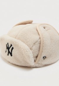 Chapeau trapper en polaire couleur crème avec logo "NY" noir à l'avant et "47" brodé sur le côté, pages de l'oreille repliées.