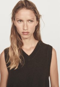 Dark brown sleeveless sweater with a V-neck, knit texture, and a subtle ribbed edge, featuring a simple, clean design.