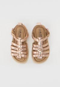 Sandales métalliques en bronze avec des brides, semelles plates, sangle de cheville ajustable et finition texturée. Doublure intérieure de couleur beige. Taille 24.