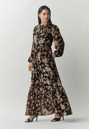 Maxikleid aus schwarzem Stoff mit floralem Muster in Beige und Pink. Mit langen Ärmeln, hohem Kragen, elastischer Taille und Rüschen-Saum versehen.