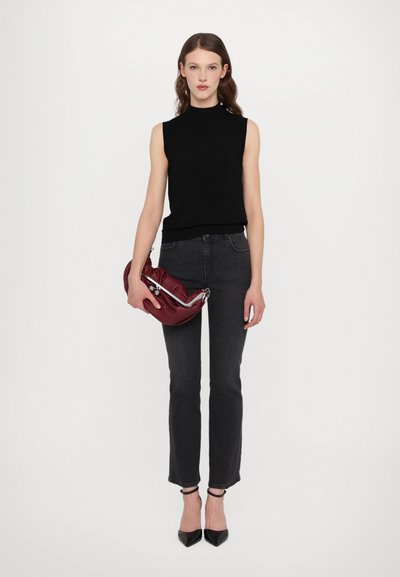 Sort ærmeløs top, grå lige jeans og sorte spidse hæle. Holder en rød læder clutch med sølv hardware detaljer.