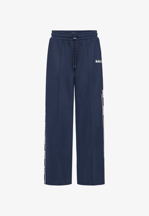 Pantalons de survêtement bleu marine en tissu texturé, dotés d'une taille élastique avec cordon de serrage et d'un logo blanc le long des coutures latérales. Design ample.