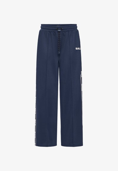 Pantalons de survêtement bleu marine en tissu texturé, dotés d'une taille élastique avec cordon de serrage et d'un logo blanc le long des coutures latérales. Design ample.