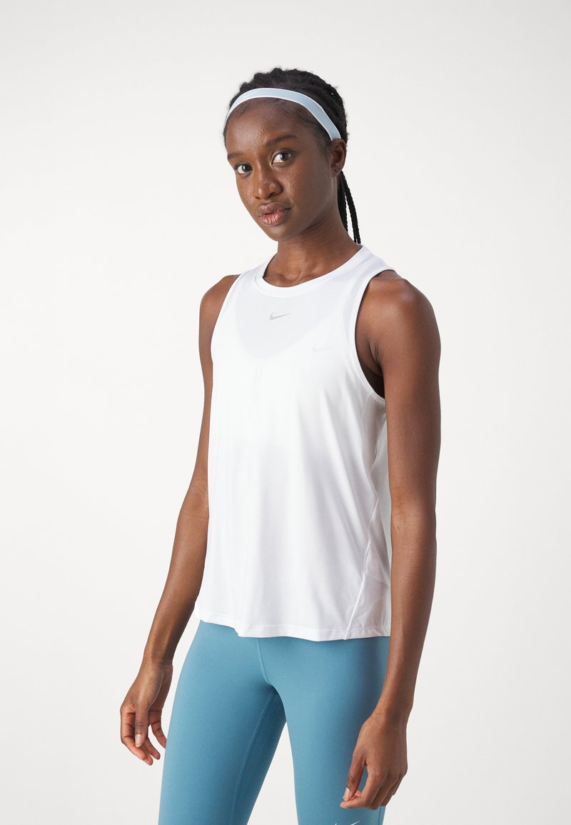 Top deportivo blanco sin mangas con escote redondo, fabricado en una tela suave y ligera. Combinado con leggins azules.