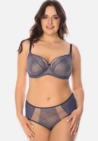 Completo di lingerie in pizzo blu navy che presenta un reggiseno strutturato con dettagli in rete e un fiocco decorativo, abbinato a mutandine in pizzo trasparente a vita alta.