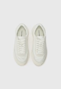 Calvin Klein white sneakers feature a smooth, textured upper with a padded collar, lace-up closure, and a chunky rubber outsole.
