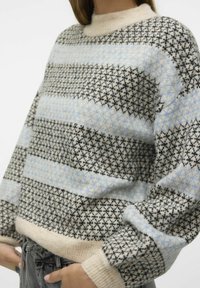 Gebreide sweater in crème, zwart en lichtblauw. Bevat een patroon van diagonale strepen en een textuurachtige stof. Ronde halslijn en geribde mouwen.