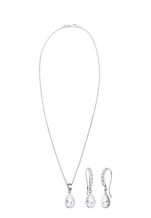 Collana d'argento e orecchini pendenti coordinati con pietre preziose trasparenti a forma di pera e delicati anelli di catena con una finitura lucida.