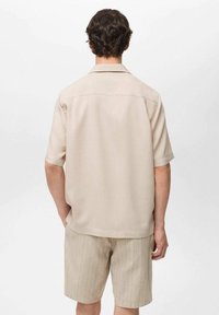 Beige overhemd met korte mouwen, een rechte snit, subtiele glans en ronde kraag, gecombineerd met lichtbeige gestreepte shorts.
