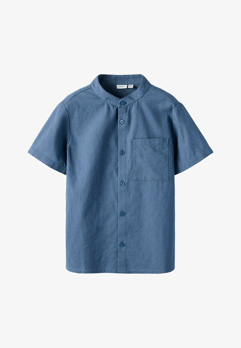 Chemise à manches courtes en tissu bleu moyen, avec un col mandarin, une poche poitrine simple et une finition texturée.