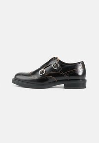 Zwarte leren dresschoenen met een brogue ontwerp, dubbele gespsluitingen, contrasterende bruine stiksels en een stevige zwarte rubberen zool.