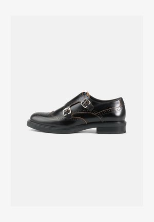 Svarta läderskor med brogue-design, dubbelspännen, kontrasterande bruna sömmar och en robust svart gummisula.