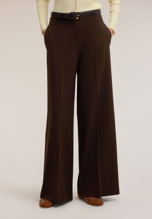 Brązowe spodnie o szerokich nogawkach z gładką fakturą, z bocznymi kieszeniami i paskiem w talii. Wykończone okrągłą klamrą.
