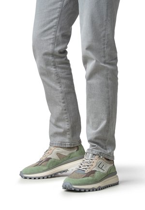 Groene en beige sneakers met gestructureerde stof en suède accenten, voorzien van een dikke beige zool en een grijze rubberen profielzool.