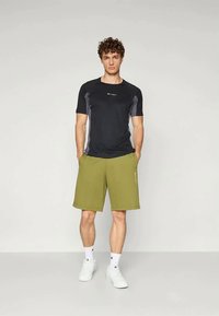 Must mustar  t-särk hallide aktsentidega, koos oliiviroheliste lühikestega; lihtne disain, valmistatud kergest kangast, kantud valgete tossudega.