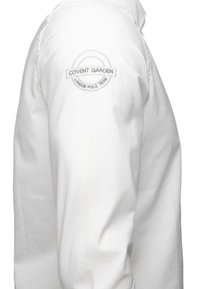 Camicia bianca a maniche lunghe con un logo rotondo ricamato sulla spalla sinistra che riporta la scritta "Covent Garden London Polo Team."