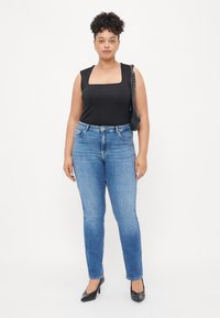 Black square-neck tank top, blue slim-fit jeans, and black high-heeled shoes. Simple design with slight texture in the jeans.