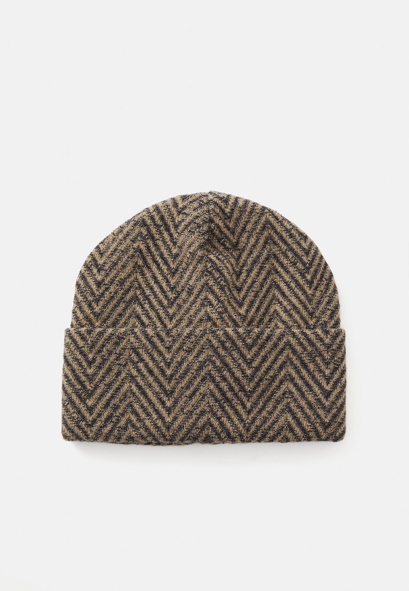 Căciulă tricotată cu model herringbone în nuanțe de maro și negru, pliată, cu margine răsfrântă, pe un fundal alb.