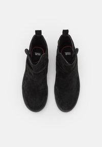 Botine negre din suede, cu o textură moale, având un stil relaxat, tăietură joasă și un design minimalist, cu un logo subtil pe interior.