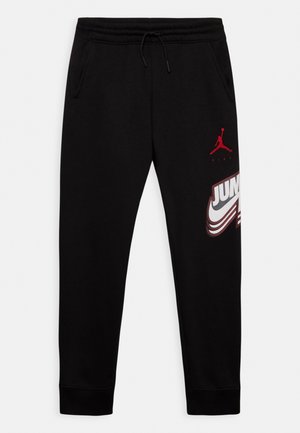 Zwarte Nike Jordan joggingbroek met elastische tailleband, trekkoord, zijzakken, rode Jumpman-logo en grote "JUMP"-print op het rechterbeen.