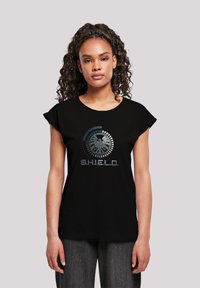 Svart t-skjorte med rund hals og korte ermer, med grafisk design av et emblem og teksten "S.H.I.E.L.D." i grå og blå toner.